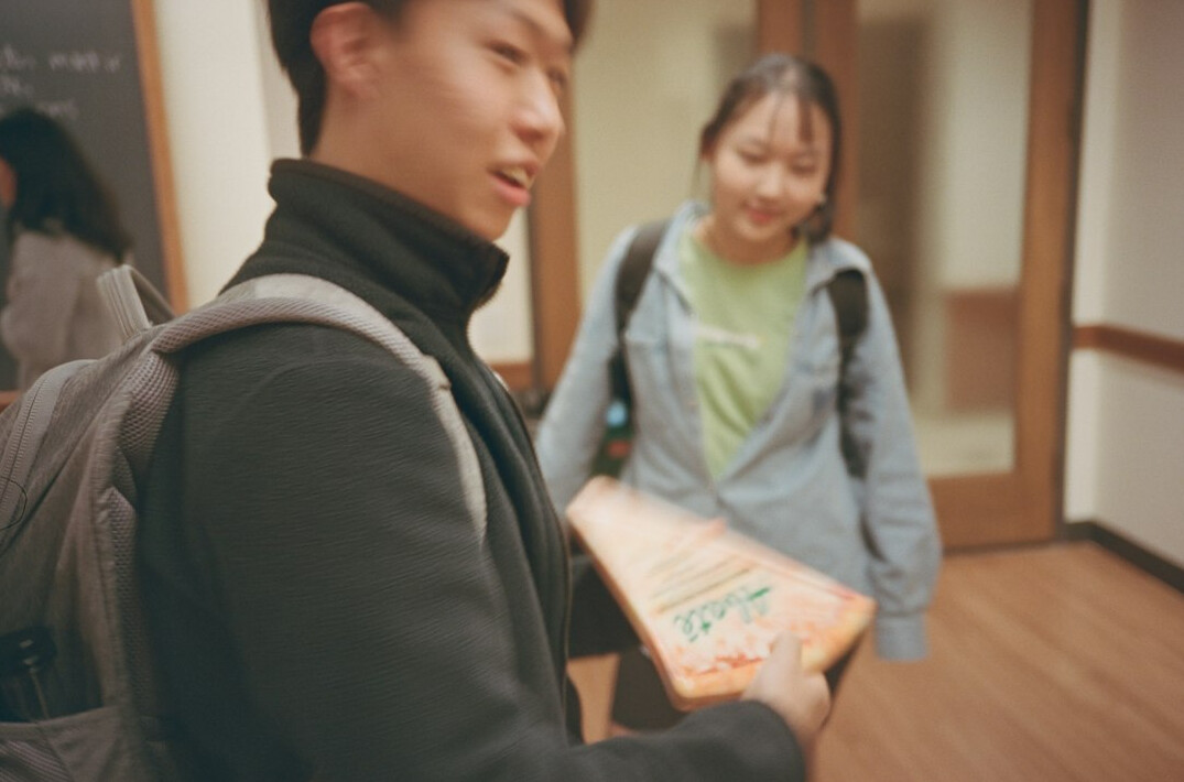 Japanese mentor helping a student review code on a laptop